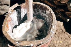 Tibetischer Pastoralist in einer Winterweide beim Kneten von Yakmilch zur Herstellung von Butter und Käse